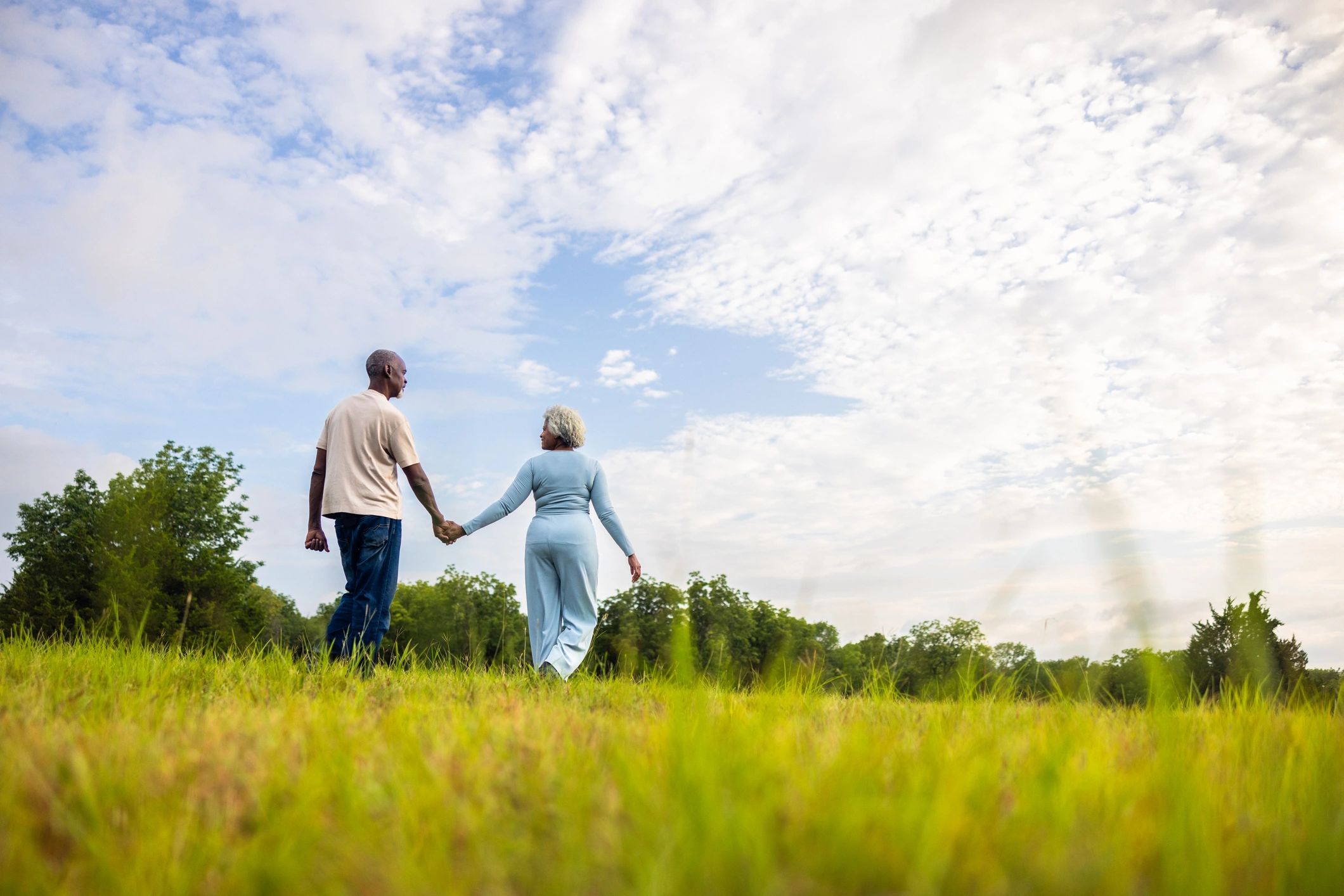 Wide shot of a senior black couple walking in a green pasture