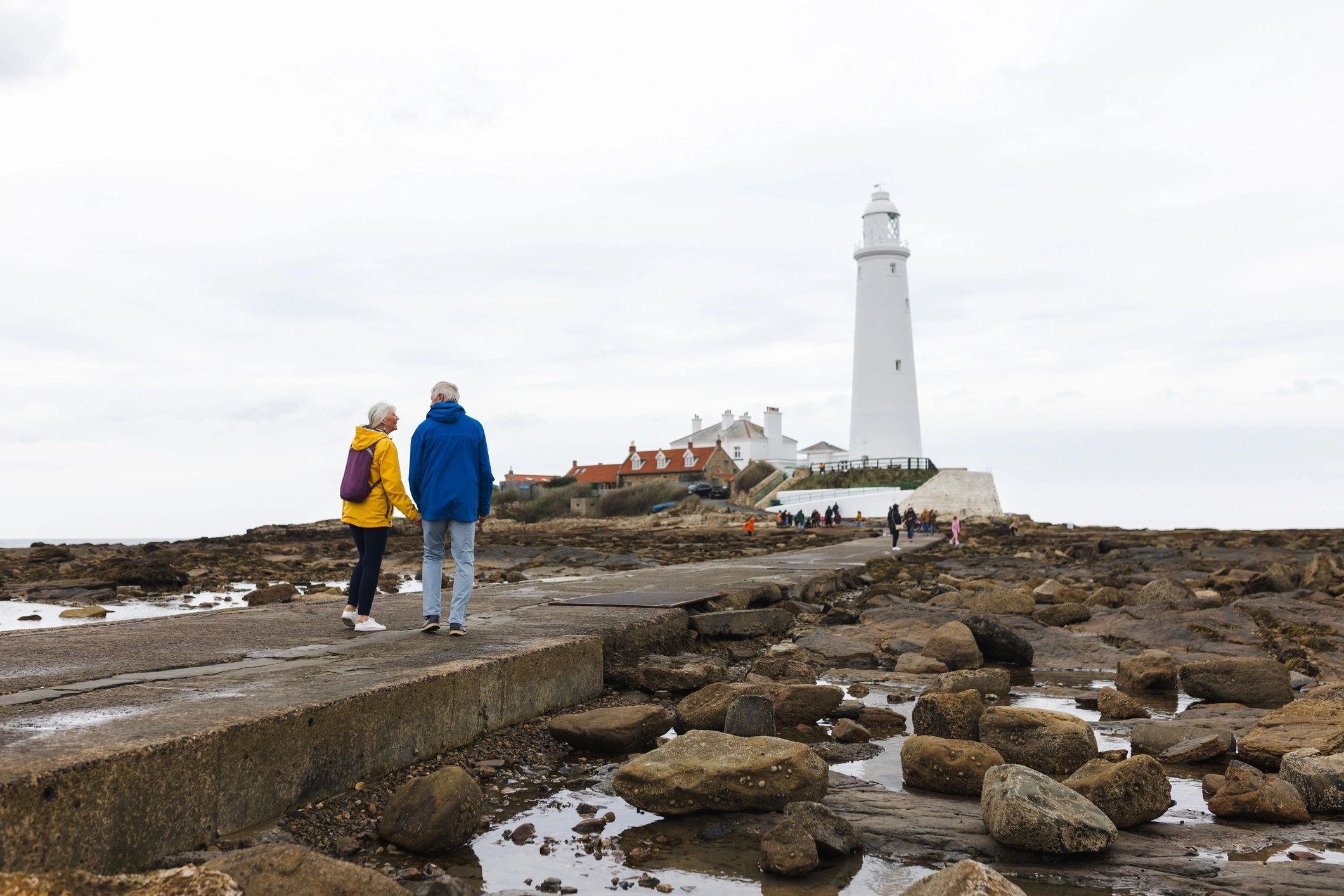 Older couple walking toward a lighthouse on a scenic coast
